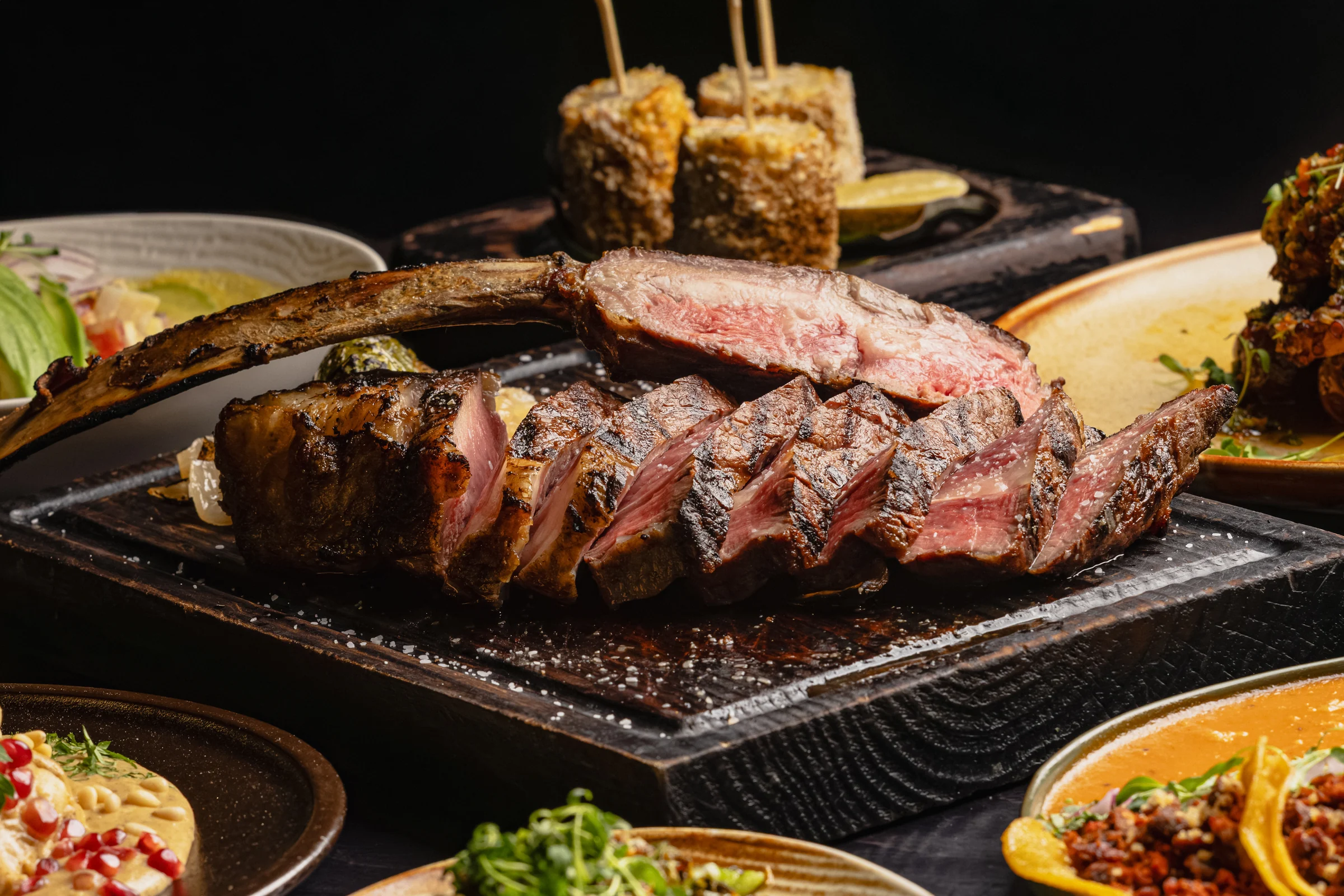 An Origen steak and sides spread on a wooden board