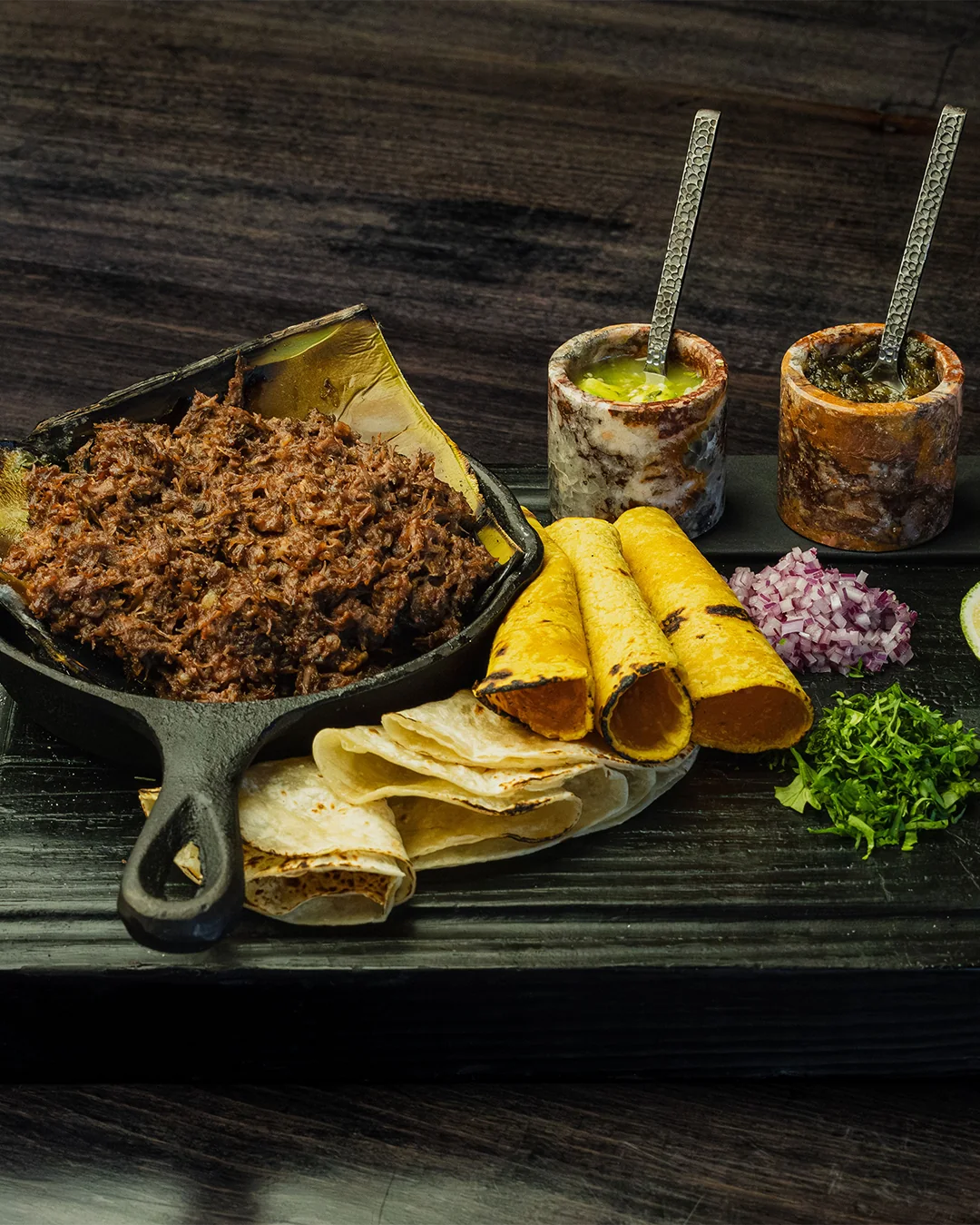 A generous brunch platter with shredded meat, tortillas and colorful salsas at Origen Gilbert